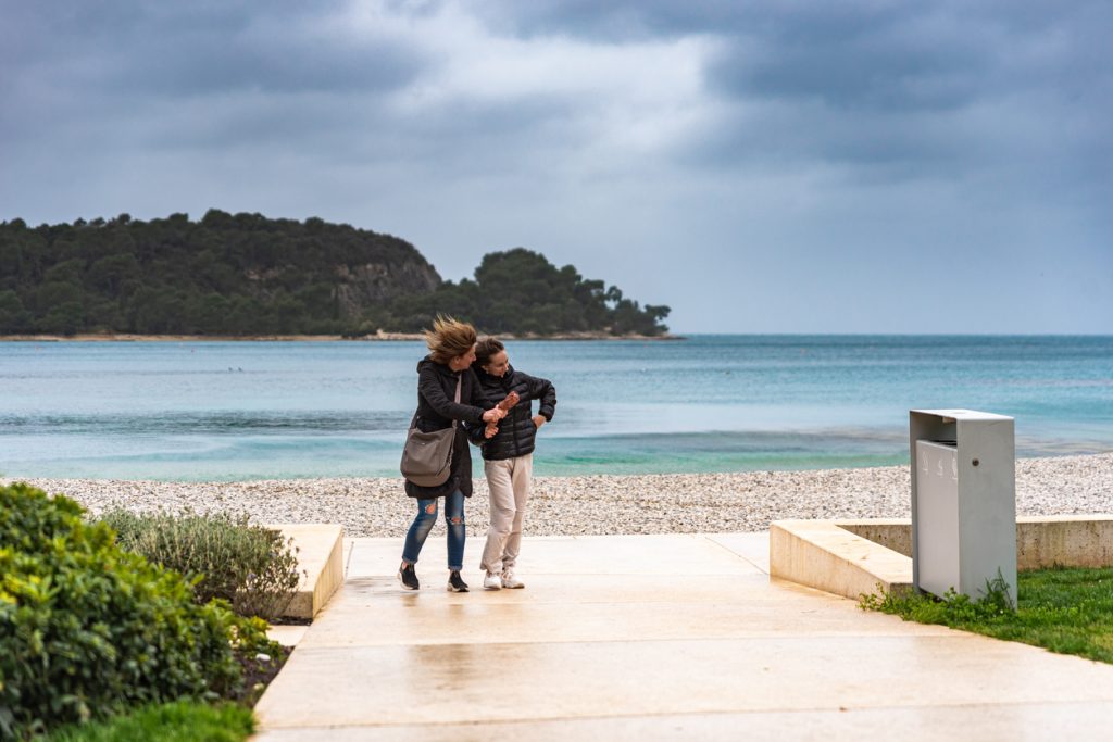 A Rovinj beach in the winter - mother and daughter walking on a windy day
