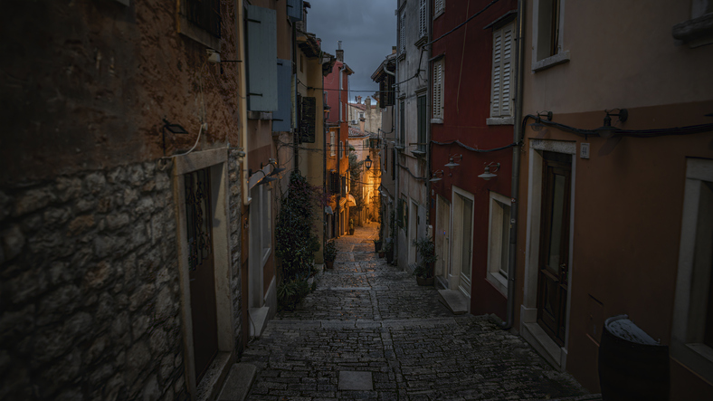 Cobblestone city streets of old traditional Croatian town Rovinj in Istria. The town is illuminated by the warm light of old street lanterns.
