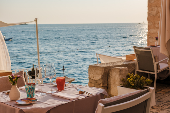 A charming table set for two invites diners to enjoy a sunset meal overlooking the shimmering waters of the Adriatic Sea in Rovinj, Croatia.
