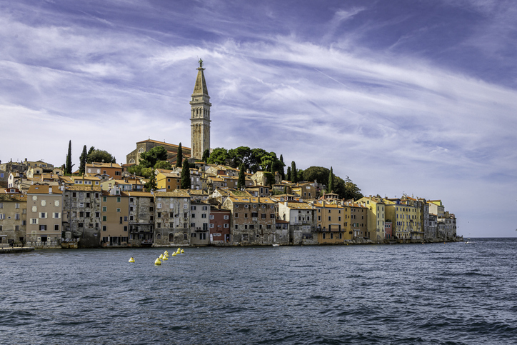 Seaside view of Rovinj's Old Town with its narrow cobblestone streets, colorful Venetian-style buildings, and the Church of St. Euphemia towering over the city.