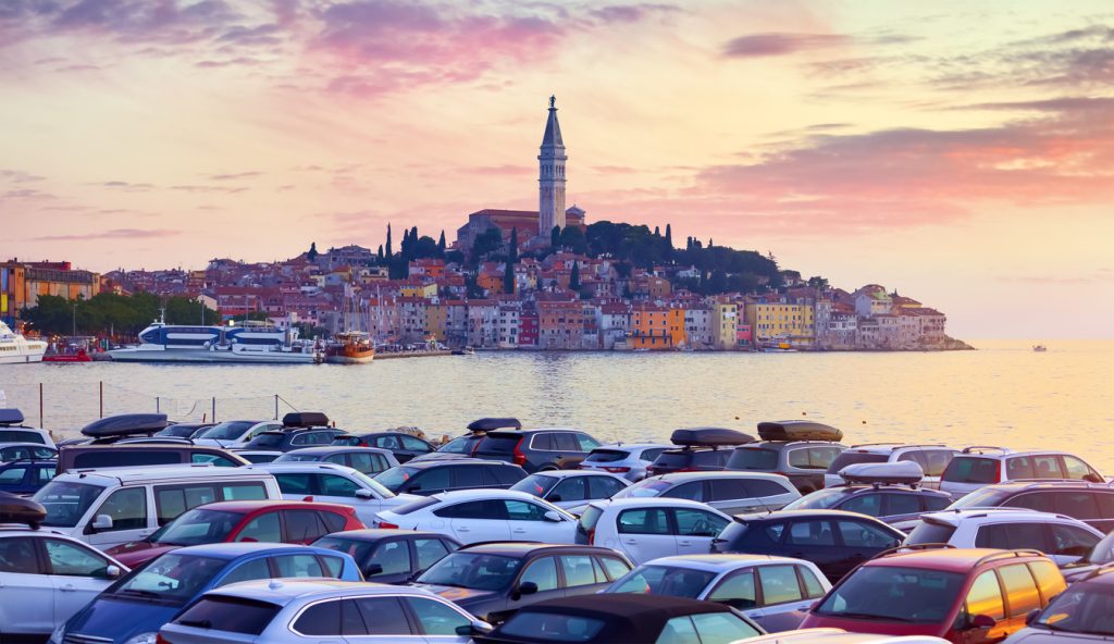Parking in Rovinj Croatia. Sunrise sky above vintage town at Istria peninsula in Adriatic Sea. View from cars parking. Old Mediterranean architecture and buildings. Coastline tower of Church Saint Euphemia